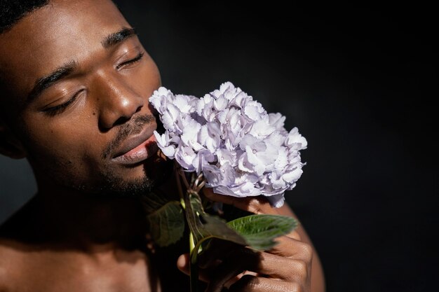 Hombre de primer plano que huele flores