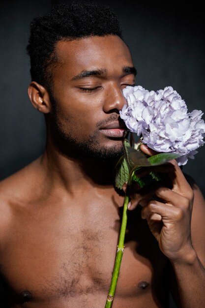 Hombre de primer plano que huele hermosa flor