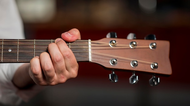 Foto gratuita hombre de primer plano sosteniendo un acorde de guitarra