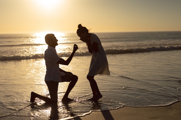 Hombre proponiendo mujer a orilla del mar en la playa