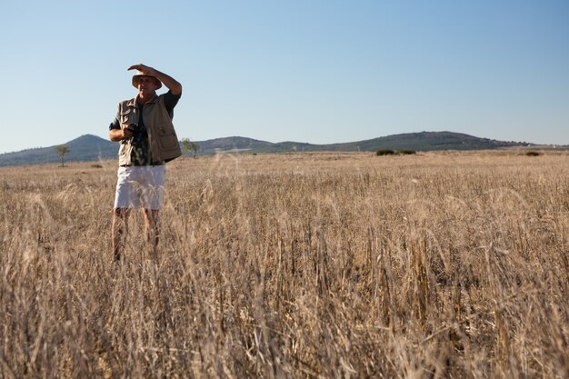 Hombre protegiendo los ojos en el paisaje