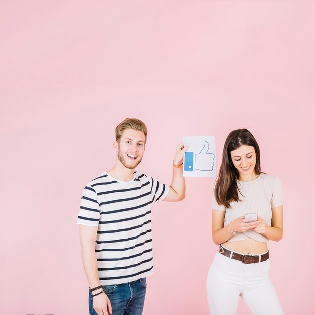 Hombre con pulgares arriba signo al lado de mujer sonriente con smartphone