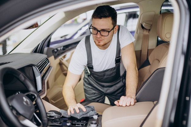 Hombre puliendo el interior del coche en el servicio de coches