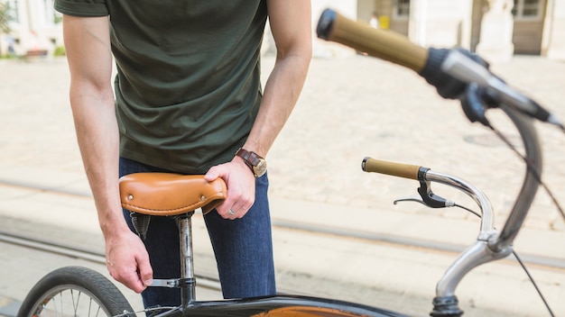 Hombre que ajusta el asiento de la bicicleta