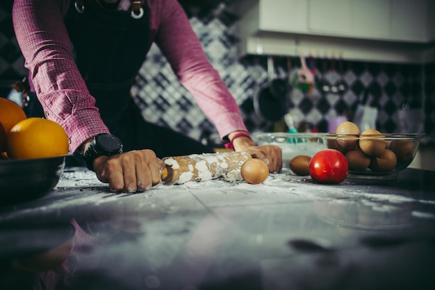 Hombre que amasa la pasta hecha en casa de la pizza en la cocina. Concepto de cocina