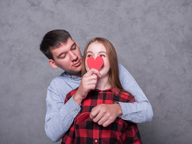 Hombre que cubre cara de mujer con corazón de papel