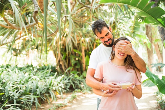 Hombre que cubre los ojos de su novia y le da su regalo sorpresa