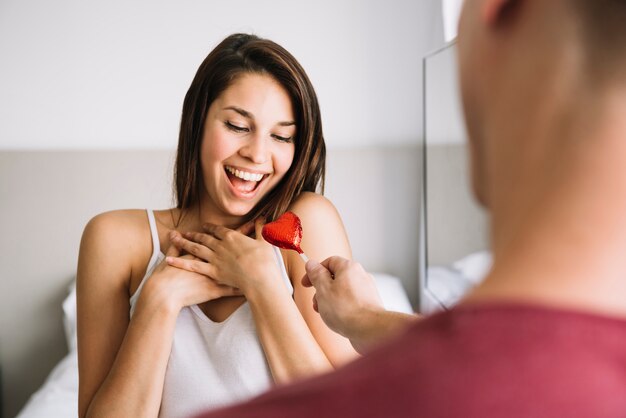 Hombre que da lollipop en forma de corazón a la mujer