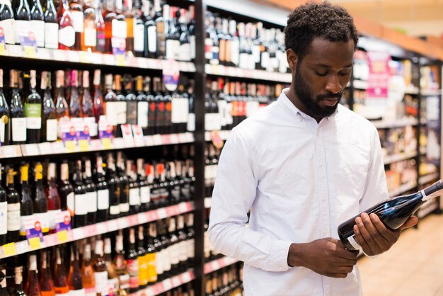 Hombre que elige la botella de vino en la sección de alcohol