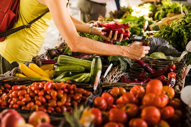 Hombre que elige verduras de puesto de verduras en el supermercado