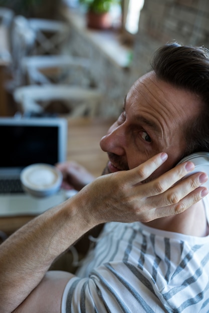 El hombre que escucha los auriculares en la cafetería