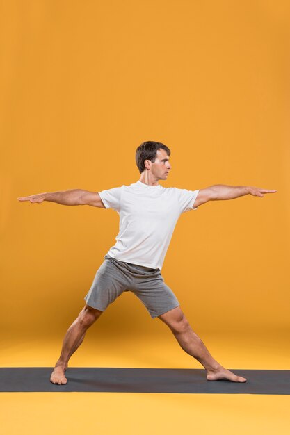 Hombre que estira en la estera de yoga