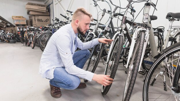 Hombre que examina el neumático de la bicicleta en tienda