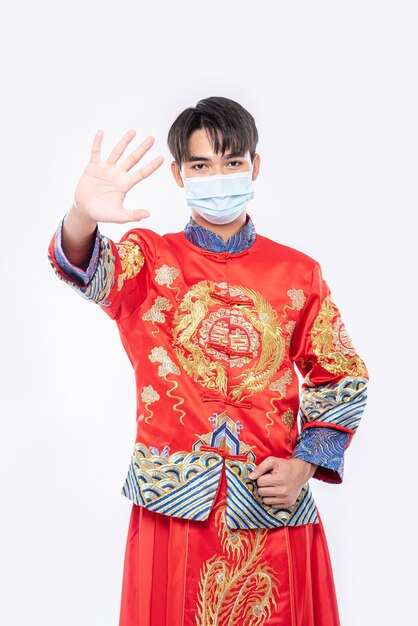 Un hombre que lleva un cheongsam y una máscara muestra que las personas que no usan máscaras no pueden comprar durante el Año Nuevo Lunar.