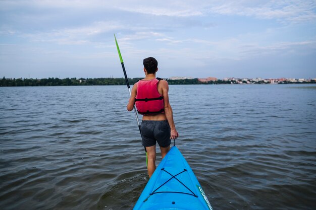 Hombre que lleva el kayak azul en el lago idílico