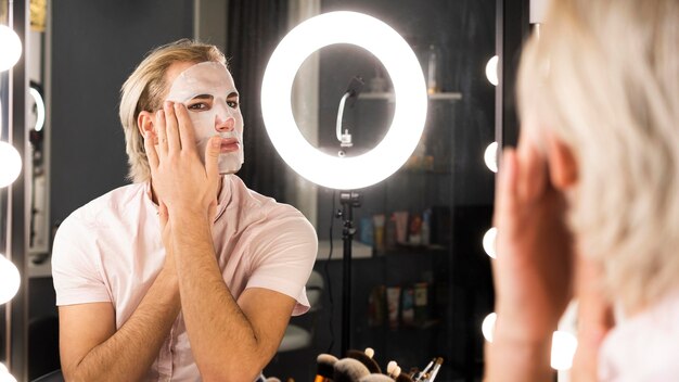 Hombre que llevaba maquillaje aplicando una mascarilla facial