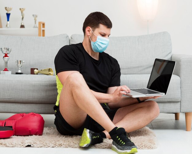 Hombre que llevaba una máscara médica mientras sostiene una computadora portátil