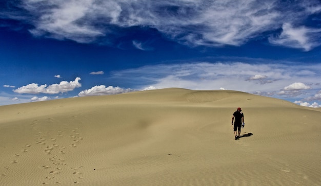 Hombre que llevaba un sombrero rojo en el desierto con un cielo azul