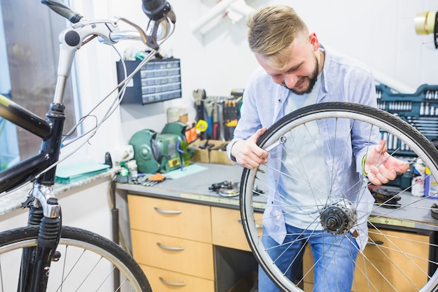 Hombre que mira el neumático de la bicicleta en taller