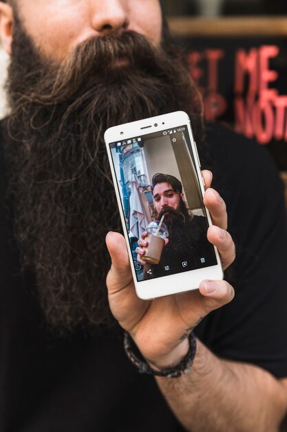 Hombre que muestra alta fotografía en la pantalla del teléfono inteligente