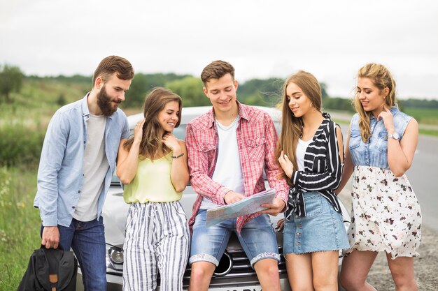 Hombre que muestra el mapa a sus amigos cerca del coche