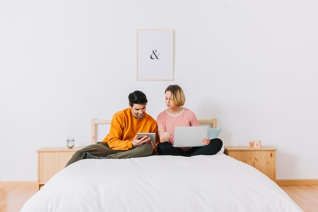 Foto gratuita hombre que muestra la tableta de la mujer en la cama