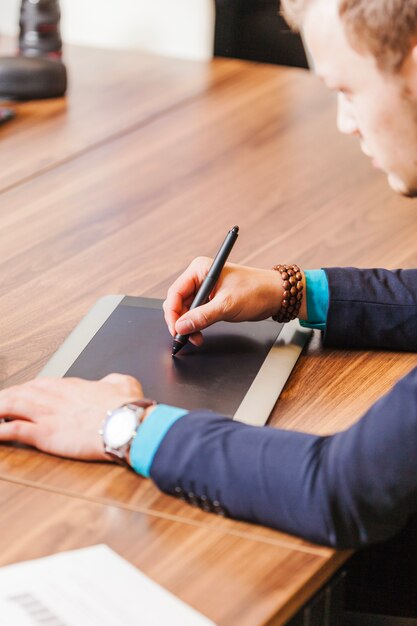 Hombre que se sienta en la escritura del escritorio con la pista