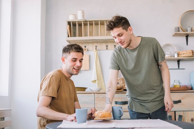 Hombre que sirve pan y café en la mesa de madera