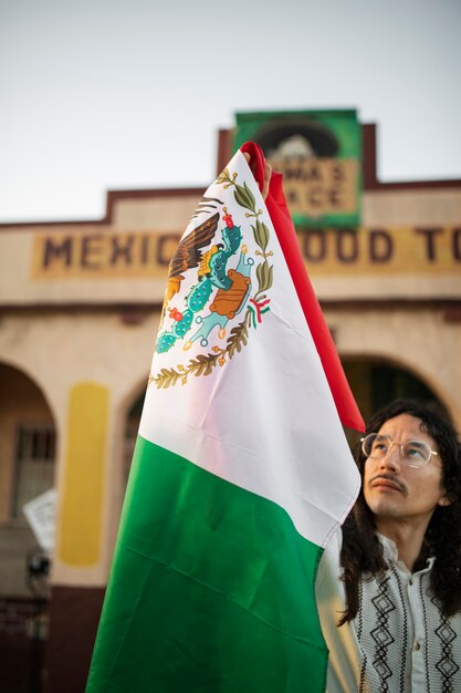 Hombre que sostiene la bandera mexicana tiro medio