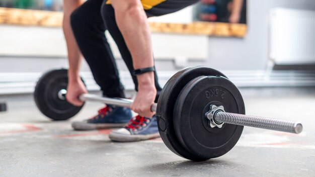 Un hombre que sostiene una barra en el piso en el gimnasio.