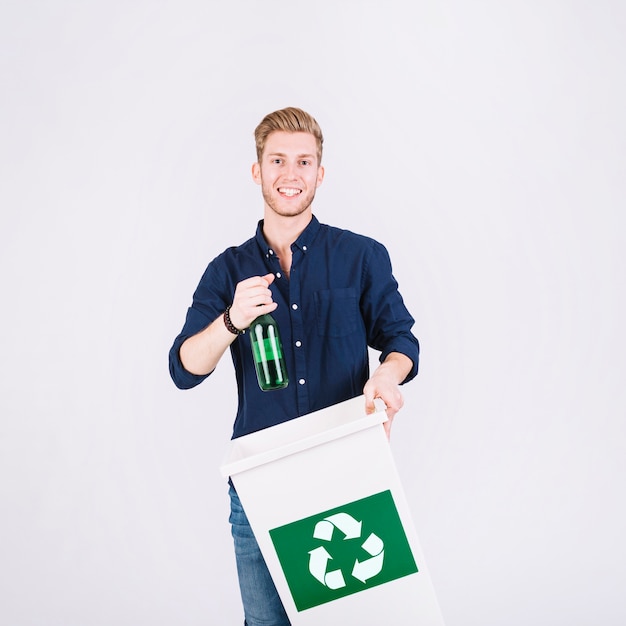 Hombre que sostiene la botella y el cubo de basura con el icono de reciclaje