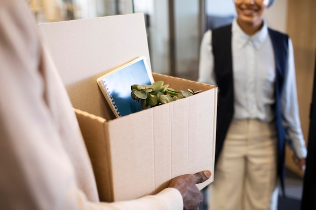 Hombre que sostiene la caja de pertenencias y se instala en su nuevo trabajo de oficina