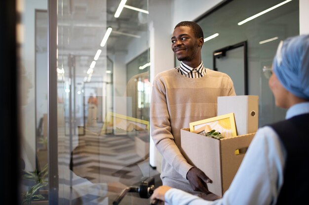 Hombre que sostiene la caja de pertenencias y se instala en su nuevo trabajo de oficina