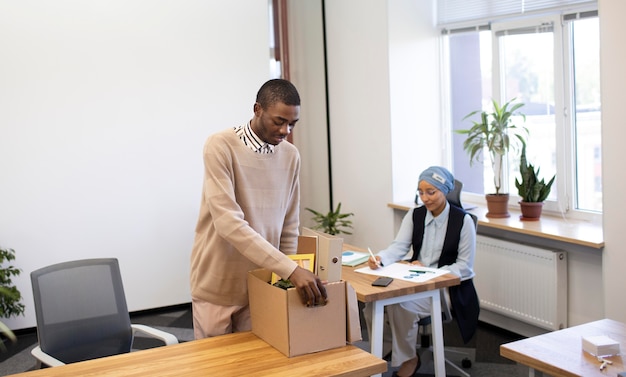 Hombre que sostiene la caja de pertenencias y se instala en su nuevo trabajo de oficina