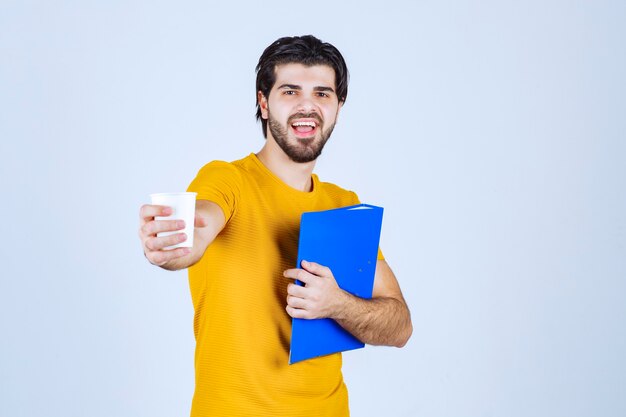 Hombre que sostiene una carpeta azul y una taza de café.