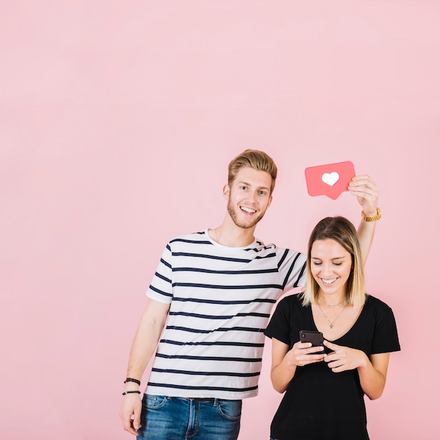 Hombre que sostiene como icono sobre mujer feliz con smartphone