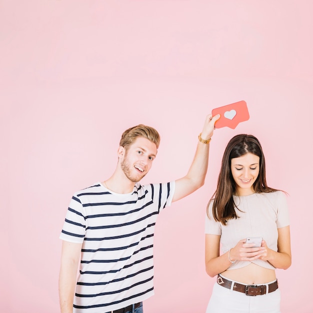 Hombre que sostiene como icono sobre su novia usando teléfono celular