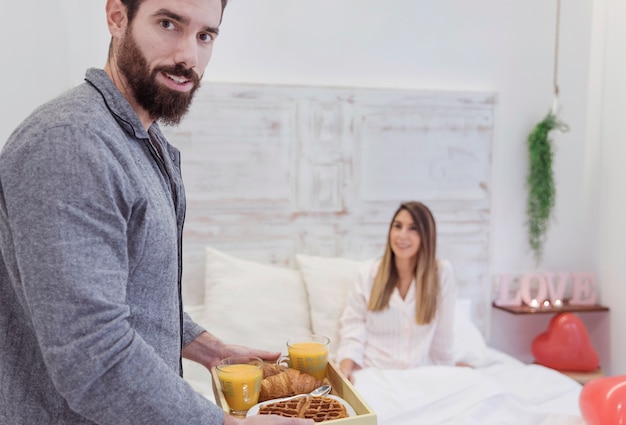 Foto gratuita hombre que sostiene el desayuno romántico en la bandeja