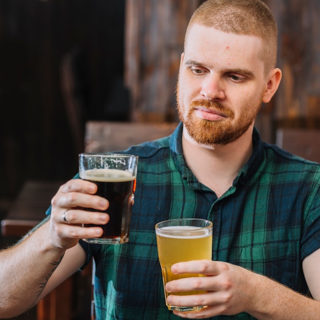 Hombre que sostiene dos tipos diferentes de bebidas alcohólicas