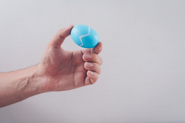 Hombre que sostiene un huevo de Pascua en el fondo blanco.