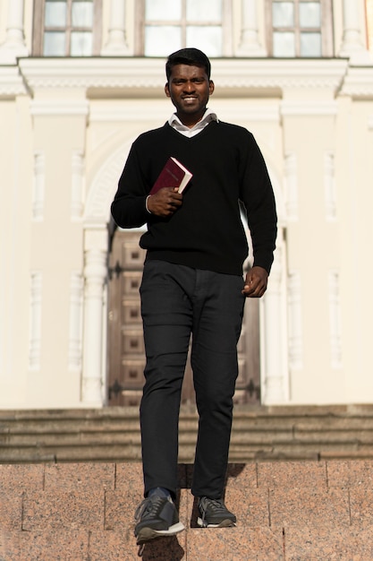 Foto gratuita hombre que sostiene el libro de la biblia fuera de la iglesia