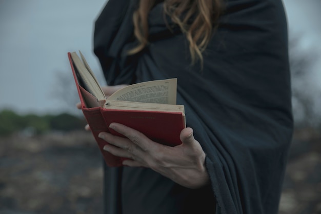 Hombre que sostiene un libro rojo afuera