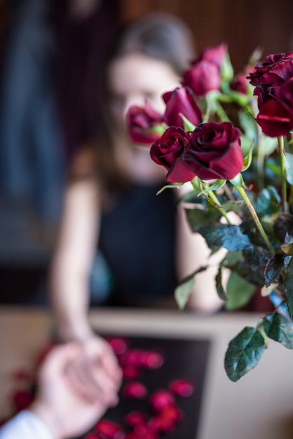 Hombre que sostiene la mano de la mujer cerca de ramo de flores