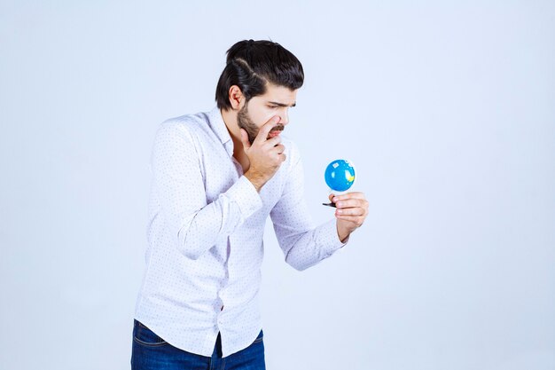 Hombre que sostiene un mini globo y parece confundido