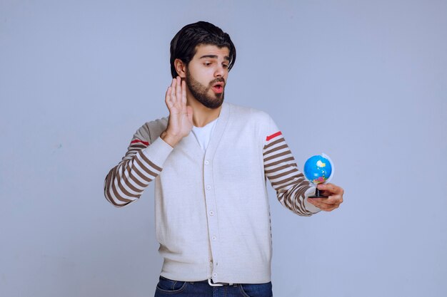 Hombre que sostiene un mini globo y parece que no tiene conocimientos de geografía.