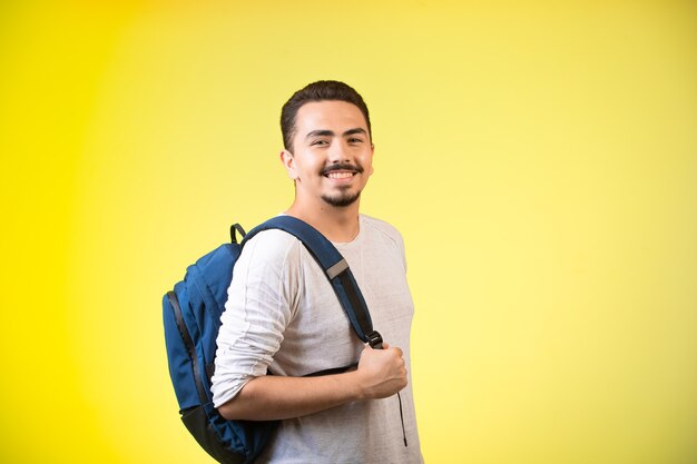 Hombre que sostiene una mochila azul y parece feliz.