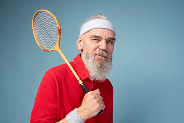 Hombre que sostiene la raqueta de bádminton tiro medio