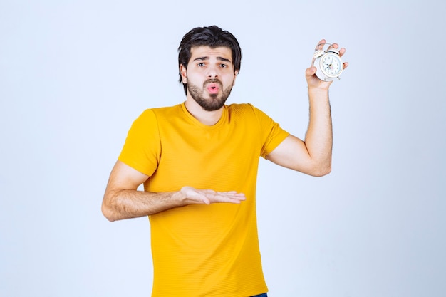 Hombre que sostiene un reloj de alarma y parece sorprendido.