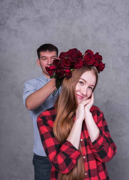 Foto gratuita hombre que sostiene rosas en la cabeza de la mujer