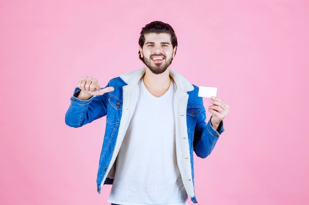 Foto gratuita hombre que sostiene su tarjeta de visita y significa su éxito